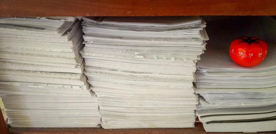 Pomodoro timer in background of paper textures piled. Stock Photos