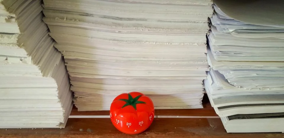 Pomodoro timer in background of paper textures piled. Foto stock
