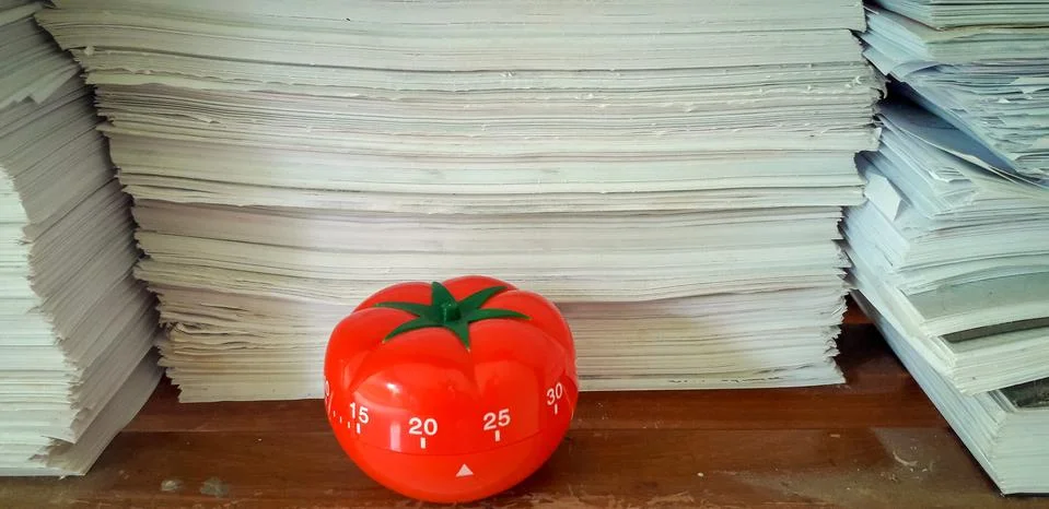 Pomodoro timer in background of paper textures piled. Stock Photos
