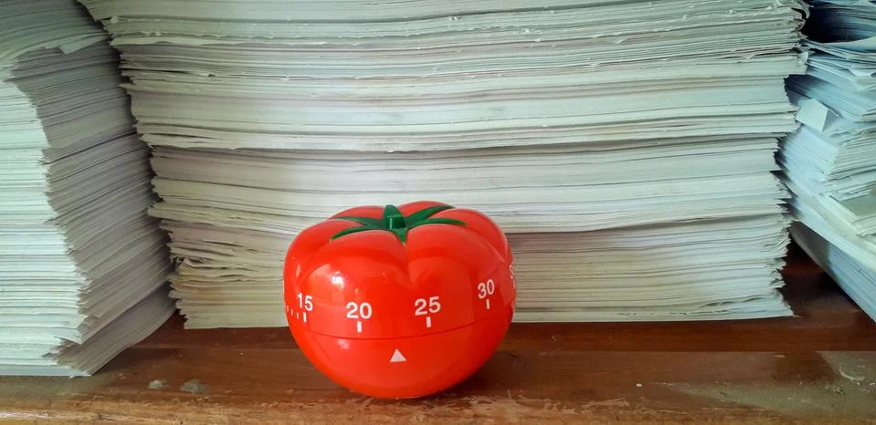 Pomodoro timer in background of paper textures piled. Stock Photos