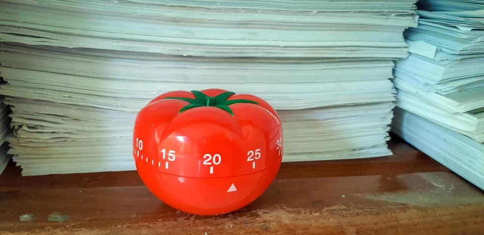 Pomodoro timer in background of paper textures piled. Foto stock