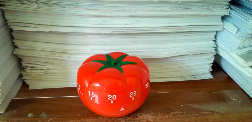 Pomodoro timer in background of paper textures piled. Stock Photos