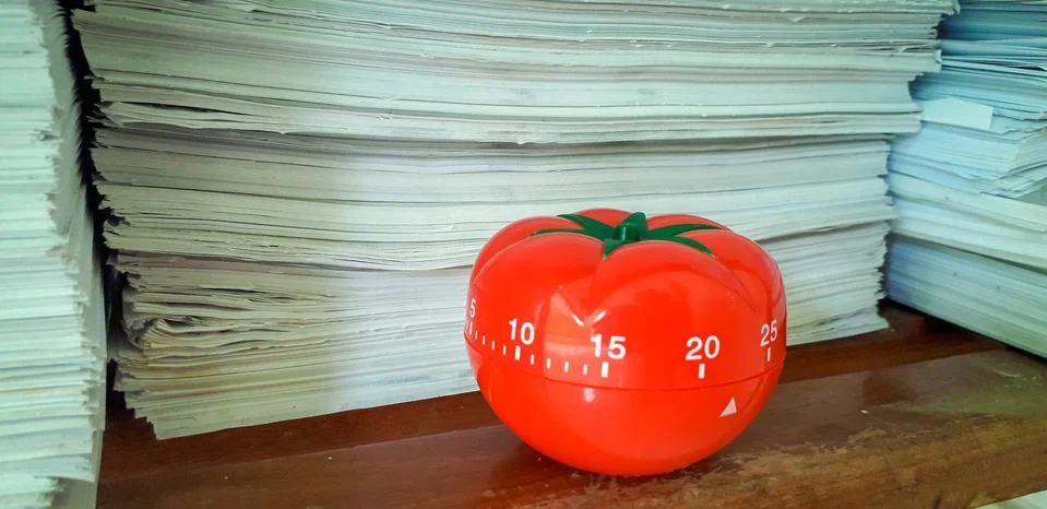 Pomodoro timer in background of paper textures piled. Stock Photos