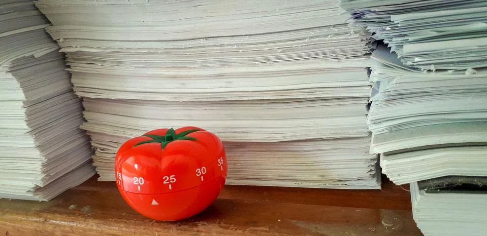 Pomodoro timer in background of paper textures piled. Stock Photos