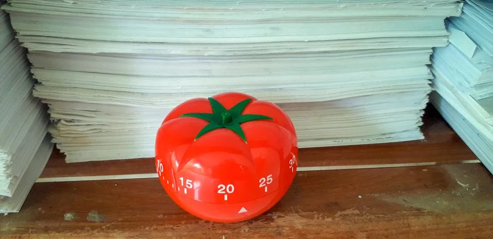 Pomodoro timer in background of paper textures piled. Stock Photos