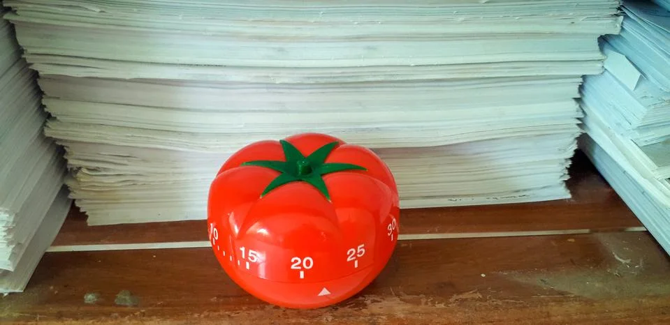 Pomodoro timer in background of paper textures piled. Stock Photos
