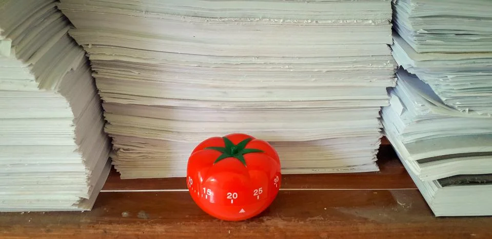 Pomodoro timer in background of paper textures piled. Stock Photos