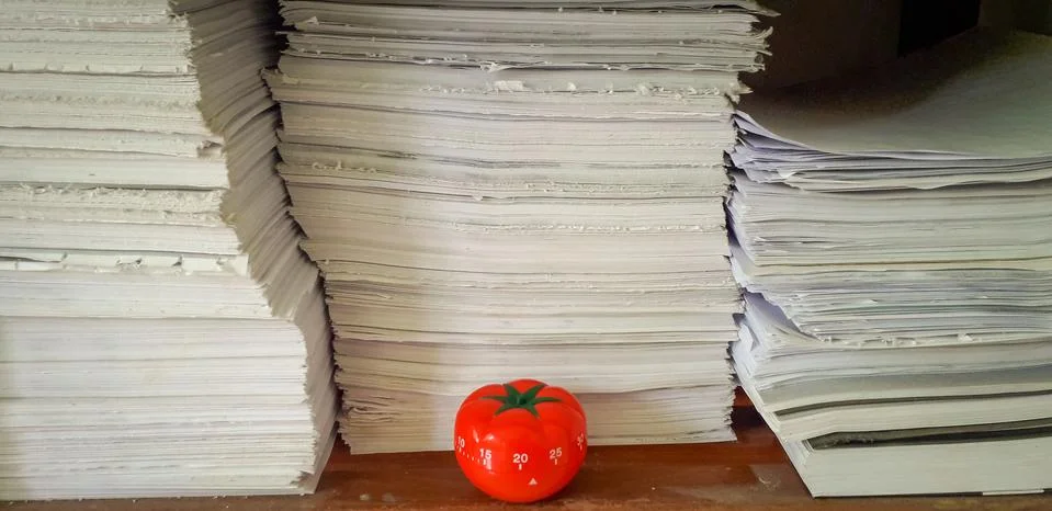 Pomodoro timer in background of paper textures piled. Stock Photos