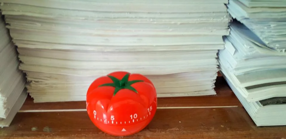 Pomodoro timer in background of paper textures piled. Stock Photos