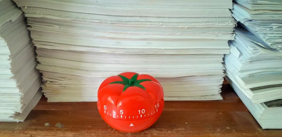 Pomodoro timer in background of paper textures piled. Stock Photos