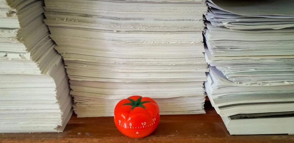 Pomodoro timer in background of paper textures piled. Foto stock
