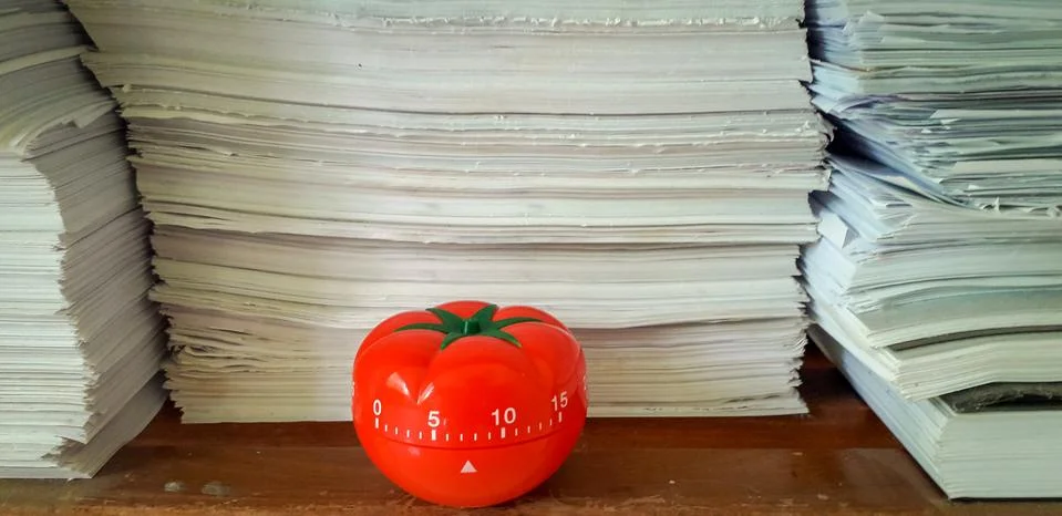 Pomodoro timer in background of paper textures piled. Stockfoto's