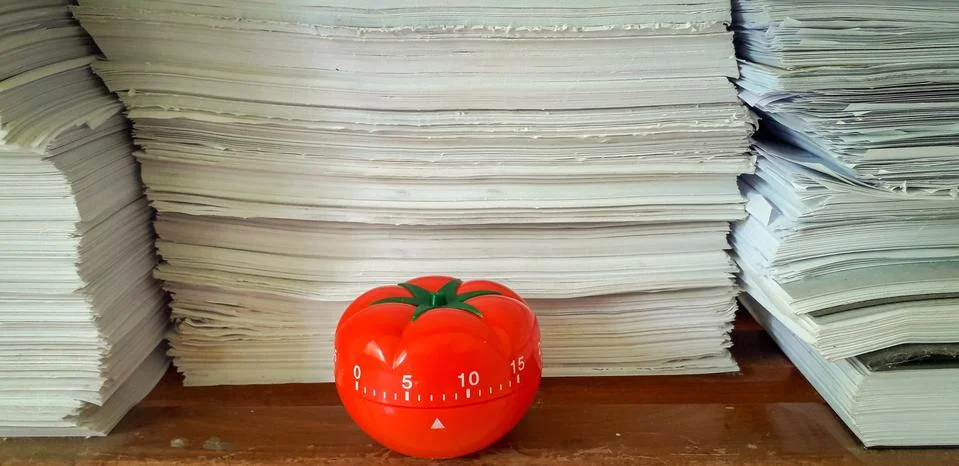 Pomodoro timer in background of paper textures piled. Stock Photos