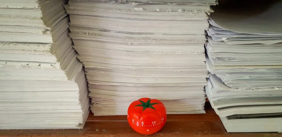 Pomodoro timer in background of paper textures piled. Stock Photos