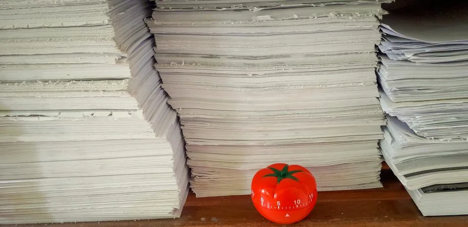Pomodoro timer in background of paper textures piled. Stock Photos