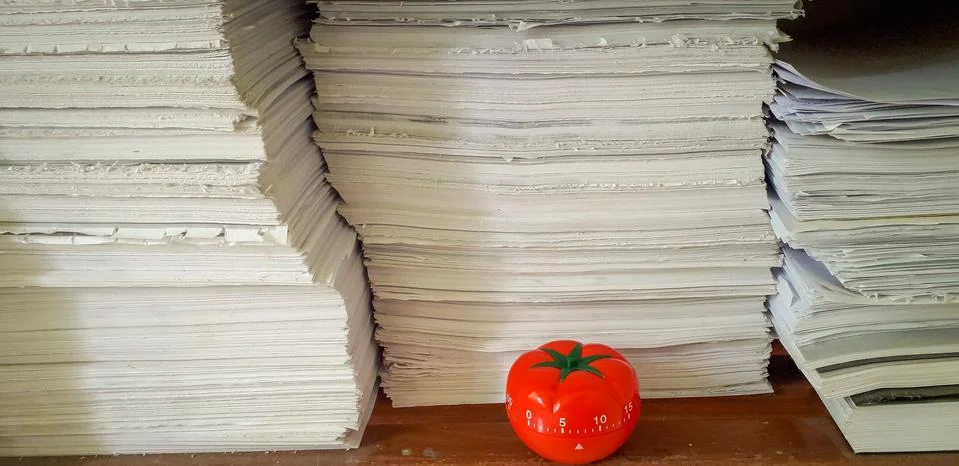Pomodoro timer in background of paper textures piled. Stock Photos