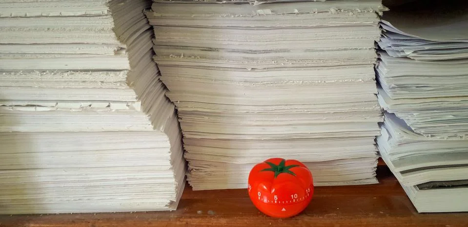Pomodoro timer in background of paper textures piled. Stock Photos
