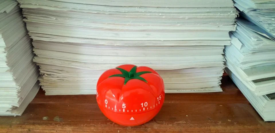 Pomodoro timer in background of paper textures piled. Stock Photos