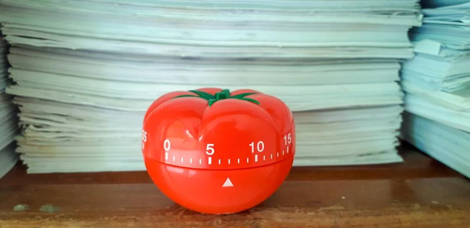 Pomodoro timer in background of paper textures piled. Stock Photos