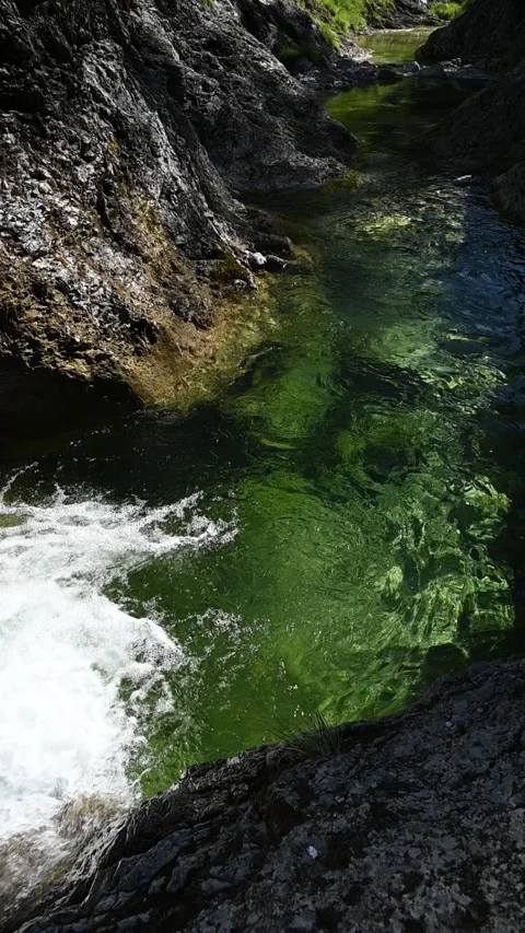 A pond inside of a v-shaped valley with the sun shining through the water Stock-Footage 260880215