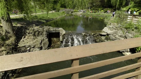 A pond running bellow a bridge at park. 4K UHD. Video stock 50144935