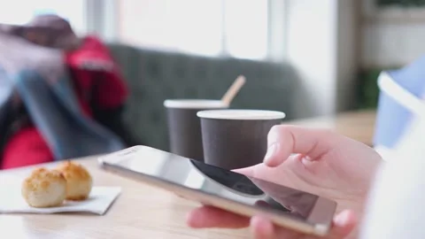 Pone in hands on the background of a cup of coffee. The girl is texting on her Stock Footage 142671602