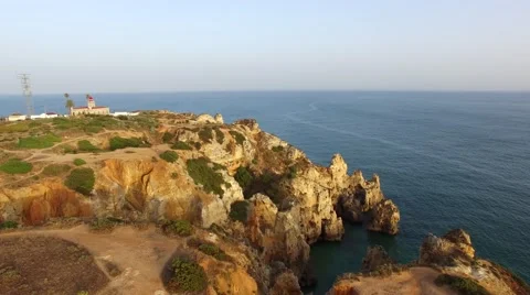 Ponta da Piedade lighthouse on cliff near ocean at sunset, Lagos, aerial view Video stock 64967311