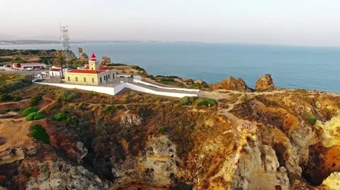 Ponta da Piedade lighthouse on cliff near ocean at sunset, Lagos, aerial view Video stock 64967658