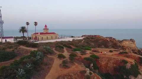 Ponta da Piedade lighthouse on cliff near ocean at sunset, Lagos, aerial view Stock Footage 64968063