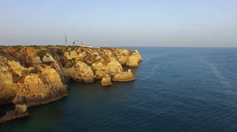 Ponta da Piedade lighthouse on cliff near ocean at sunset, Lagos, aerial view Stock Footage 64968885