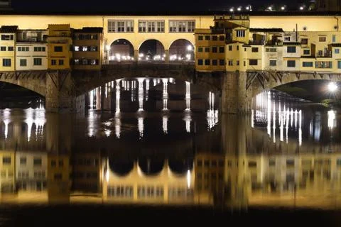 Ponte Vecchio and the reflection on the river Arno illuminated at night Stock Photos