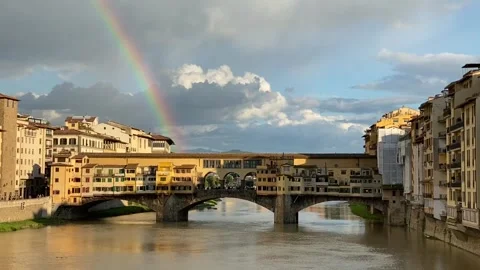 Ponte Vecchio spanning Arno River beneath rainbow and dramatic clouds in Stock Footage 346412786