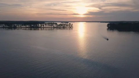 Pontoon boat approaching on lake at sunset in South Carolina Stock Footage