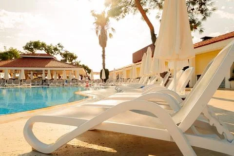 Pool area is seen with clear blue water reflecting sunlight. Chairs placed al Foto stock