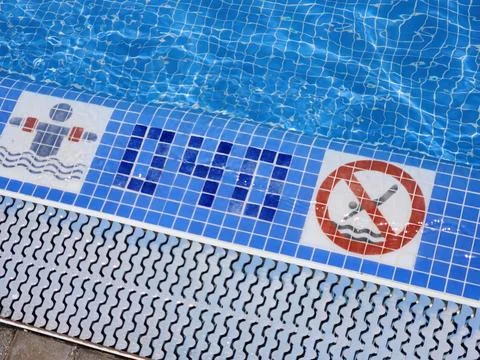 Pool border indicating pool's depth and signs regulating behavior in the pool. Stock Photos