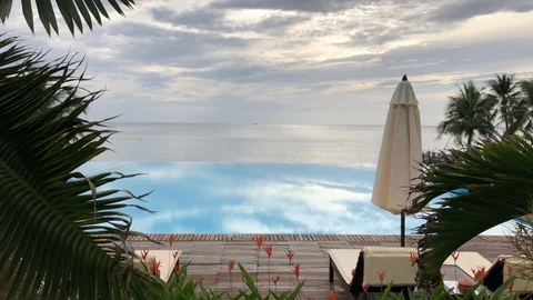 Pool deck with infinity pool and umbrella by the ocean Stock Footage 107598548