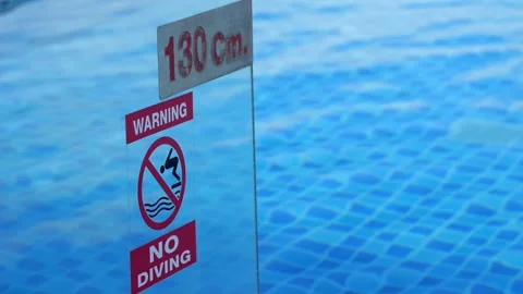 Pool depth marker stands by pool reminding swimmers to stay safe Stock Footage 302153969