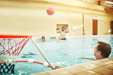 Pool, down syndrome and man with learning disability playing water basketball Stock Photos
