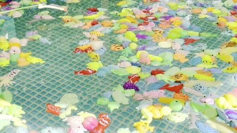 A pool is filled with many colorful plastic toys, including fish 스톡 동영상 282899837