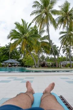Pool with a first-person view. One can see the male legs on a deck chair Foto stock