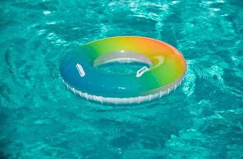 Pool float, rainbow ring floating in a refreshing blue swimming pool. Inflatable Foto stock