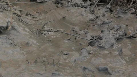 A pool of gray clay replenishes with a large surge of waste, which oily film cov Stock-Footage 122323181