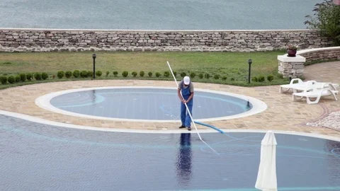 Pool guy cleaning outdoor swimming pool with a vacuum tool Stock Footage 70572809