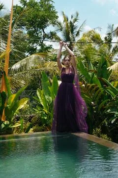 By the pool on his side stands in an evening girl dress against a backdrop of Foto stock