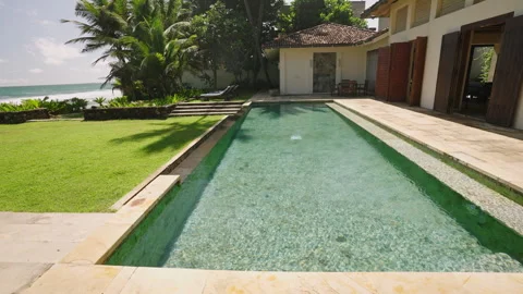 Pool in luxury villa in rays of daytime tropical sun reflects glare of light on Stock Footage 271171221