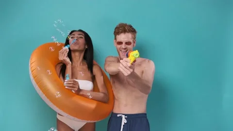 Pool party fun. Multiethnic Couple with inflatable rings having fun shooting Stock Footage 201158922