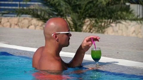 Pool party. A young bald modern caucasian man with mustache, beard sunglas 库存影片 132670134