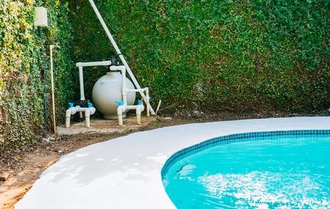 Pool pump with sand filter installed near of swimming pool. Home swimming p.. Stock Photos