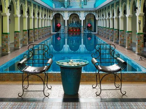 A pool surrounded by chairs and a table in a leisure area. Stock-Fotos