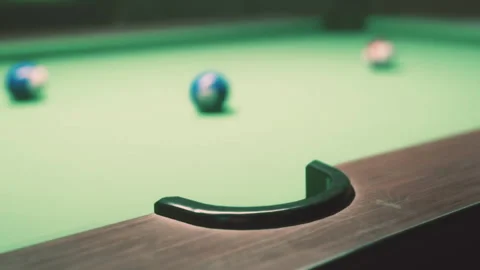 Pool table with balls in a dimly lit game room during evening hours Stock Footage 344879219